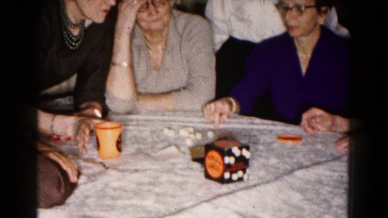 Women seated around a table with dice, an orange cup, and a black-and-orange game cube.
