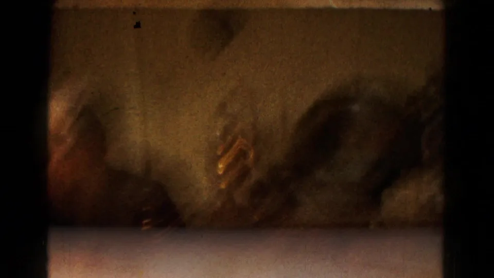 1961 Hagerstown home-movie frame showing adults around a tabletop game with small white pieces and orange tokens.