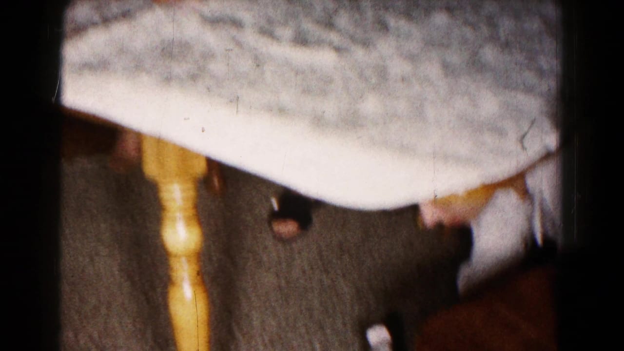 Low view beside a table with clothing, chair legs, and a person leaning down.