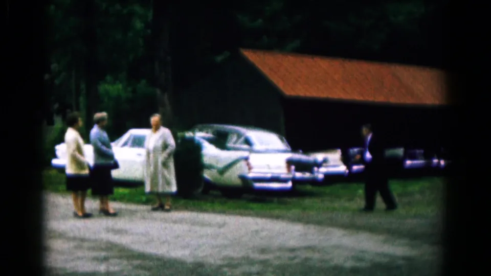 Three women remain in conversation as a suited man walks near the row of cars in the Hagerstown, Maryland footage.