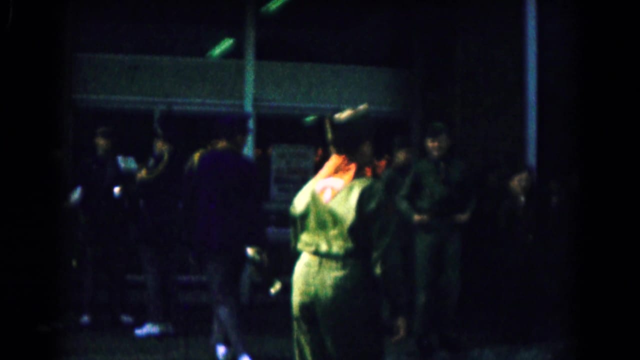 Uniformed soldiers gather outside a dimly lit building at night.