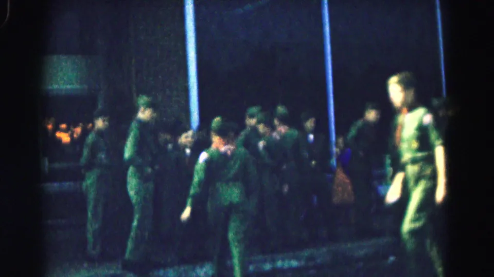 1961 Hagerstown home-movie still showing soldiers in green uniforms clustered outside a building at night.