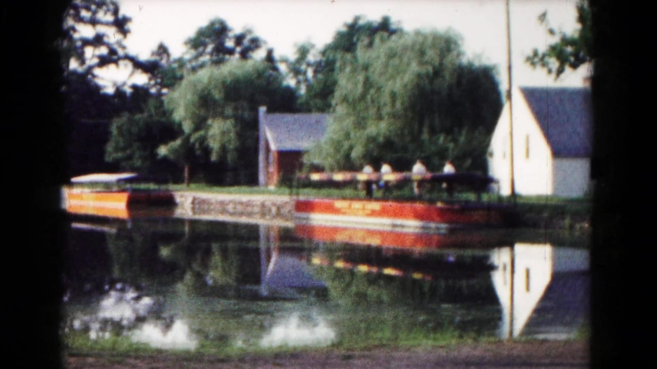 A calm park lake in Hagerstown shows a red-and-white dock or boat beside a small lakeside building and trees.