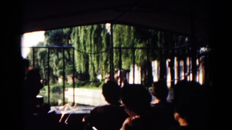 Silhouetted passengers sit under a covered boat structure in Hagerstown, Maryland, with railings, trees, and bright outdoor light ahead.