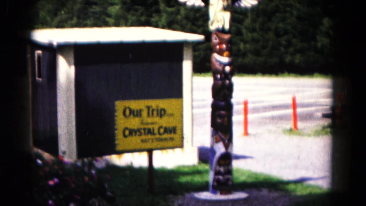 1961 Hagerstown-area home-movie frame showing a Crystal Cave entrance sign beside a small building and decorative totem-style figure.