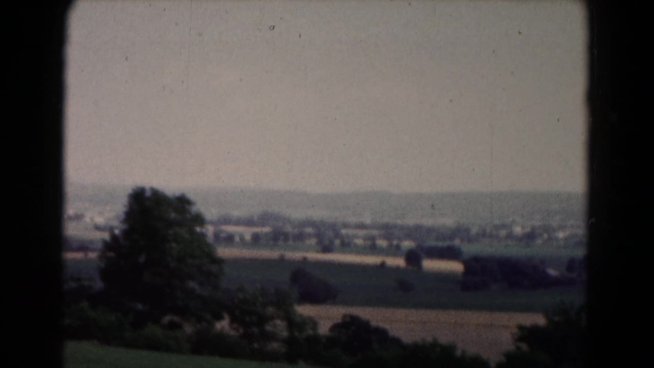 1961 8mm view near Hagerstown, Maryland, showing open fields, tree clusters, and distant buildings from an elevated position.