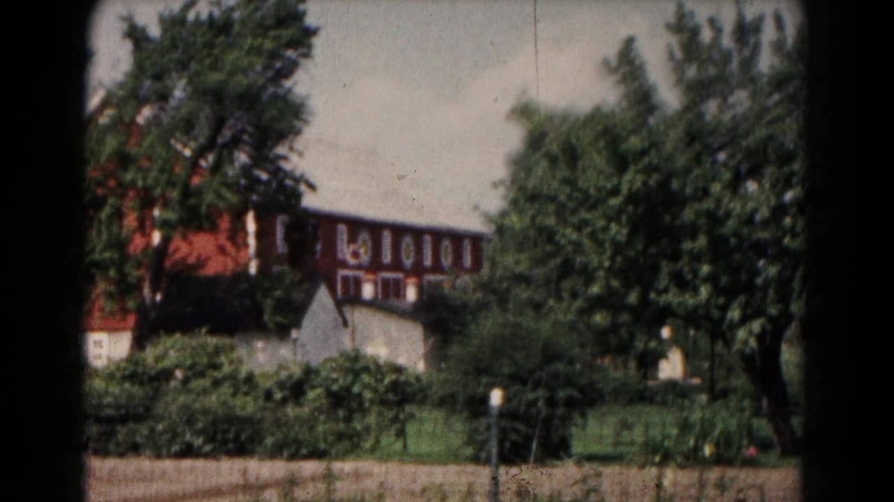 1961 rural Hagerstown view with the red barn seen through trees and a small pale outbuilding in the foreground.