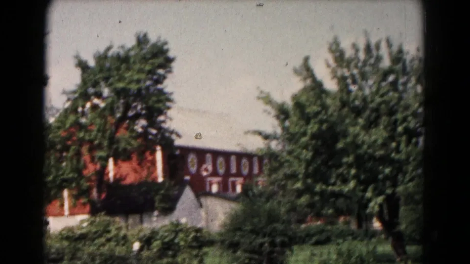 1961 Hagerstown rural exterior with a red barn, white roofline, small outbuilding, and dense summer greenery.