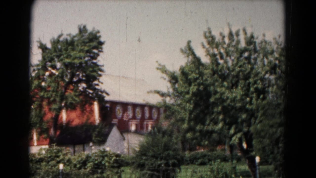 Reddish-brown building partly hidden by trees and shrubs.