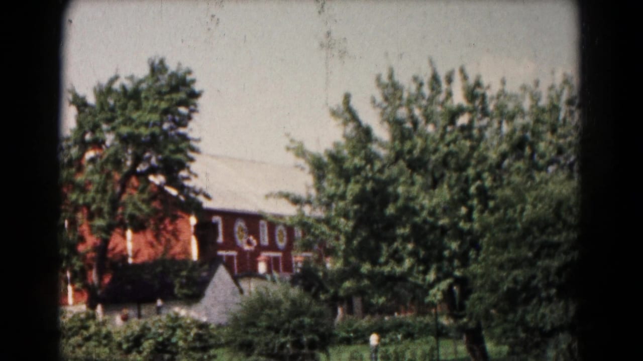 1961 Hagerstown exterior with a reddish-brown multi-story building, trees, shrubs, and a small pale structure in front.