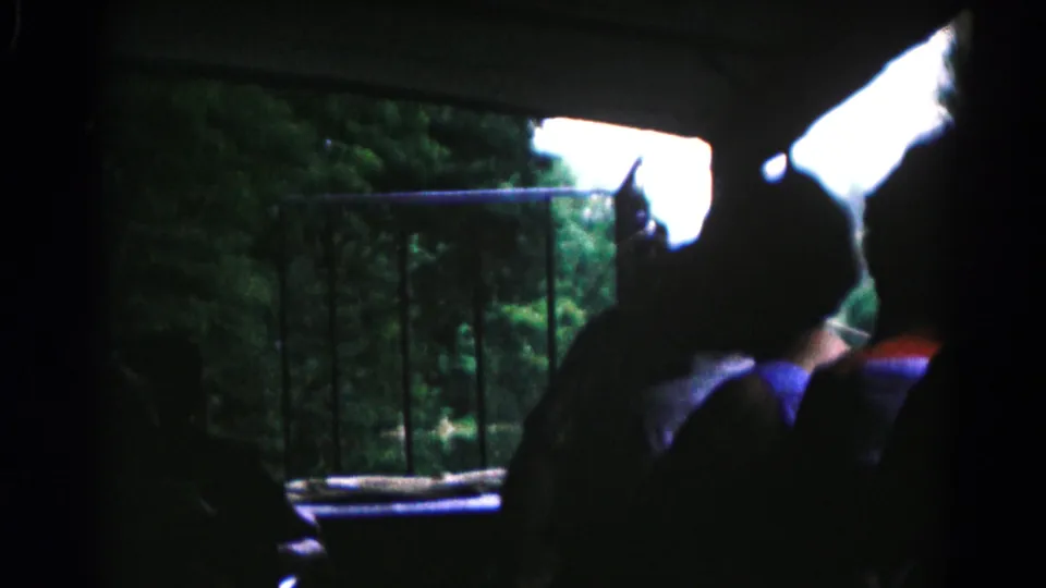 1961 8mm home-movie frame from Hagerstown, Maryland showing boat passengers in silhouette facing a wooded riverside platform.