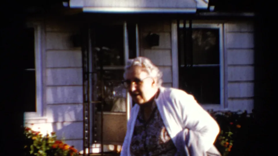 At the end of the Catskill home-movie shot, the woman moves past the camera beside the house, partially in strong sunlight.