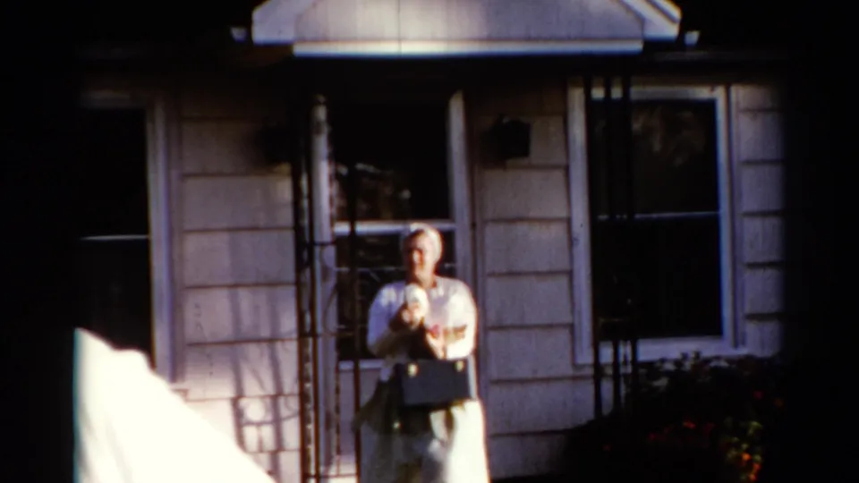 At the end of the 1962 Catskill house exterior shot, the younger woman stands near the porch holding a purse as the other woman has moved off frame.
