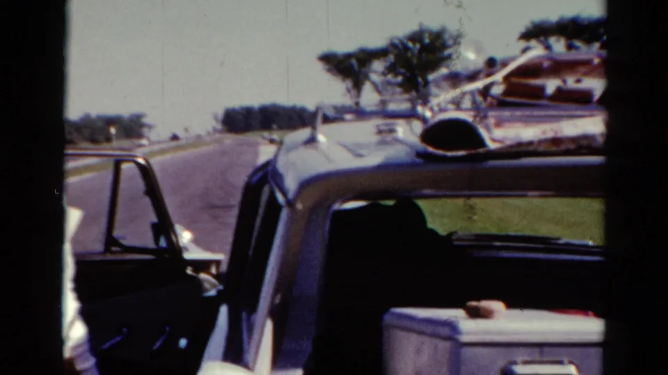 Roadside view of the vintage car, roof luggage, and open door in the Catskill, New York 1962 home-movie scene.