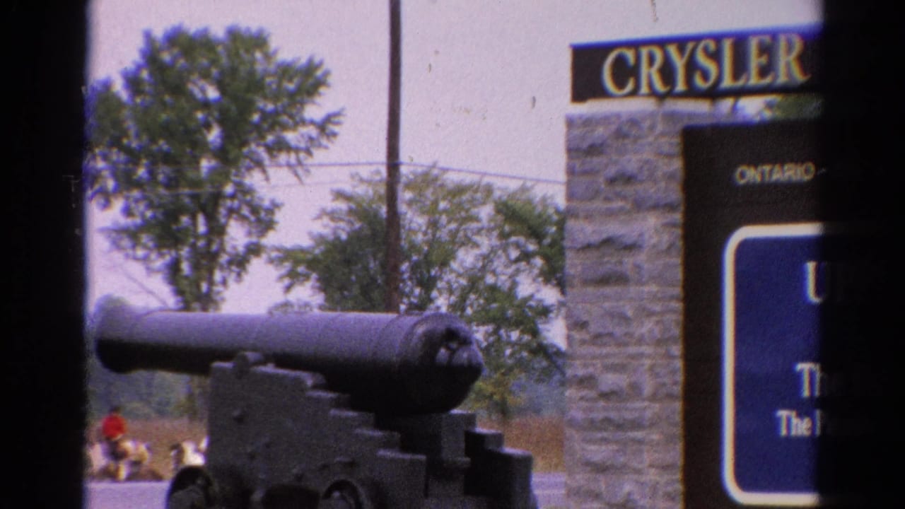 Black cannon beside a stone Cryslers Ontario sign with trees and a distant person in red.