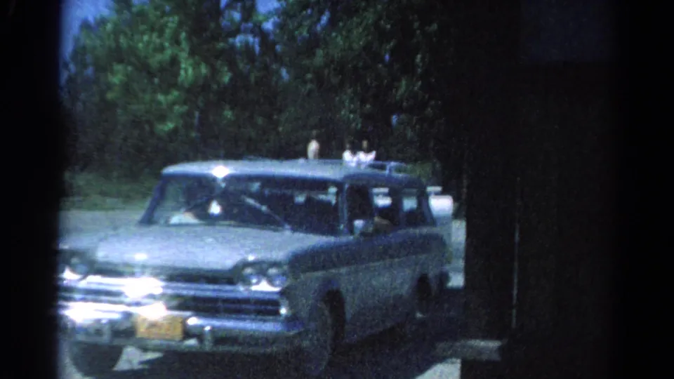 Close 1962 Catskill home-movie view of the station wagon and camper, with people visible as the vehicle passes the camera.