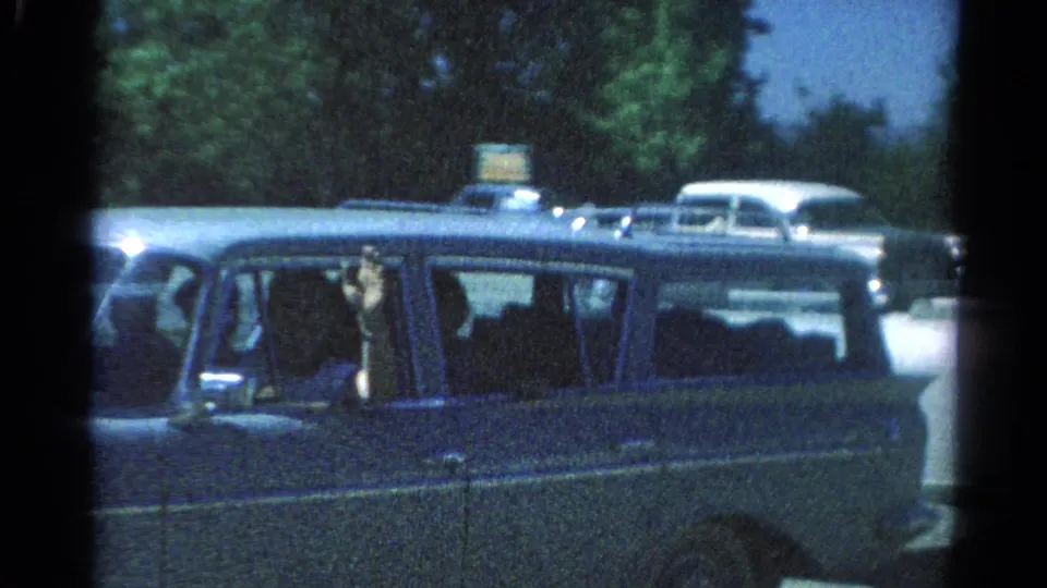 Close 8mm frame of the station wagon in Catskill, New York, with passengers visible and one person waving from the window.