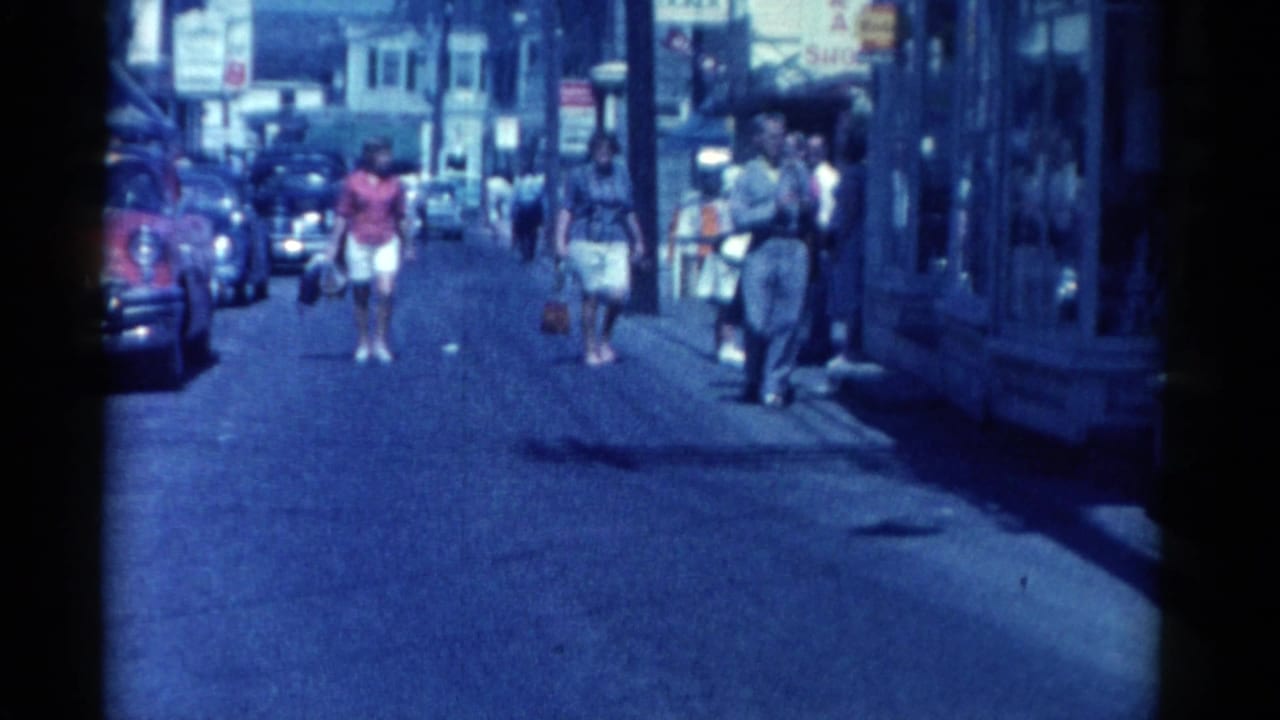 Catskill, New York street scene from 1962 with pedestrians walking between storefronts, parked cars, and visible shop signage.