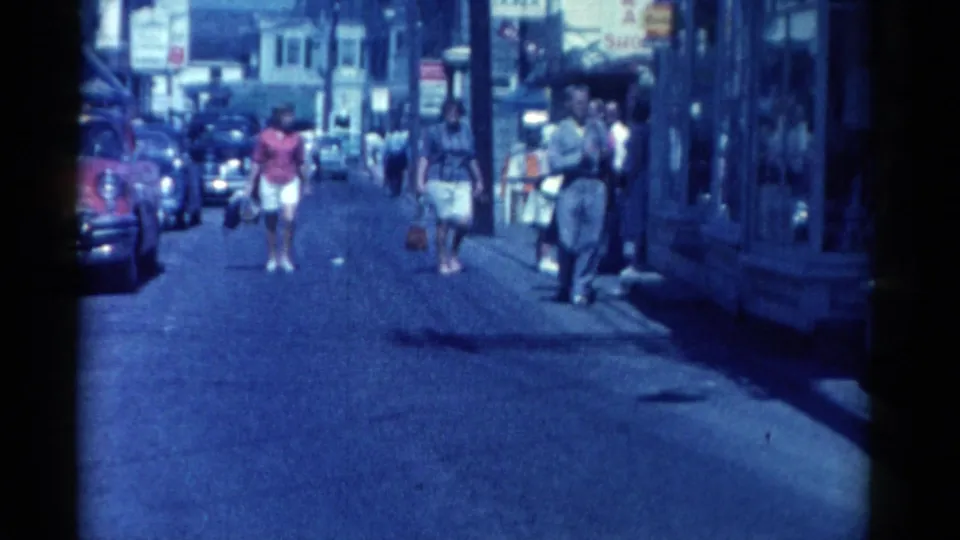 Catskill, New York street scene from 1962 with pedestrians walking between storefronts, parked cars, and visible shop signage.