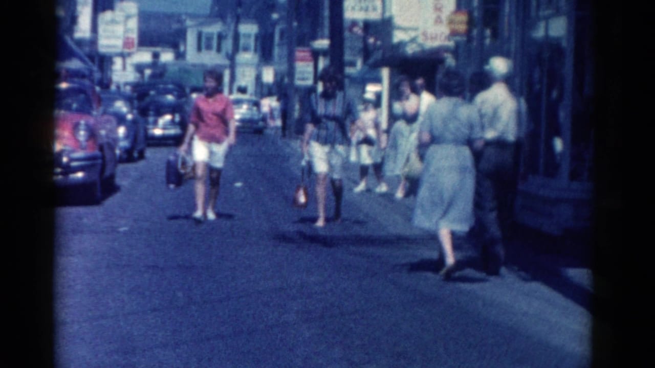 Catskill, New York street view from 1962 showing women and men walking near storefronts and early 1960s parked cars.