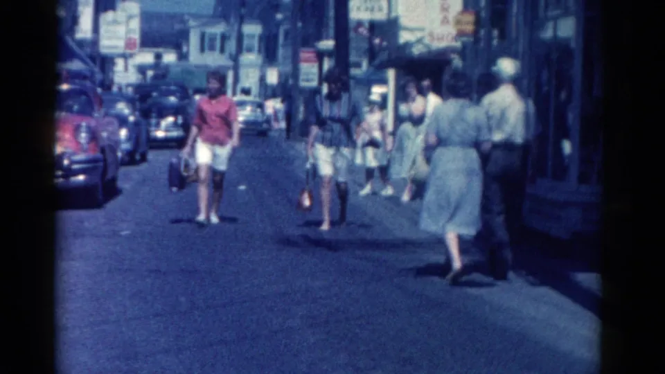 Catskill, New York street view from 1962 showing women and men walking near storefronts and early 1960s parked cars.