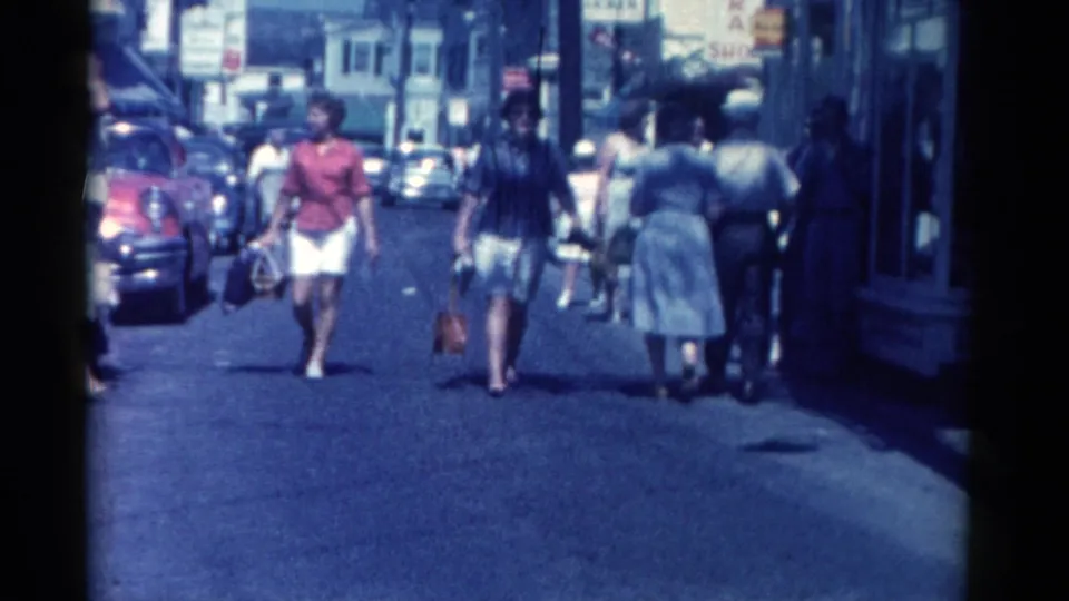 1962 Catskill downtown scene with women carrying shopping bags, men walking nearby, and classic cars parked along the street.