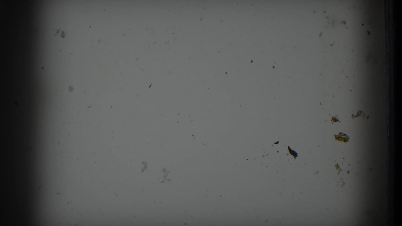 Blank or leader-like film frame with dust, marks, and dark edge vignetting.