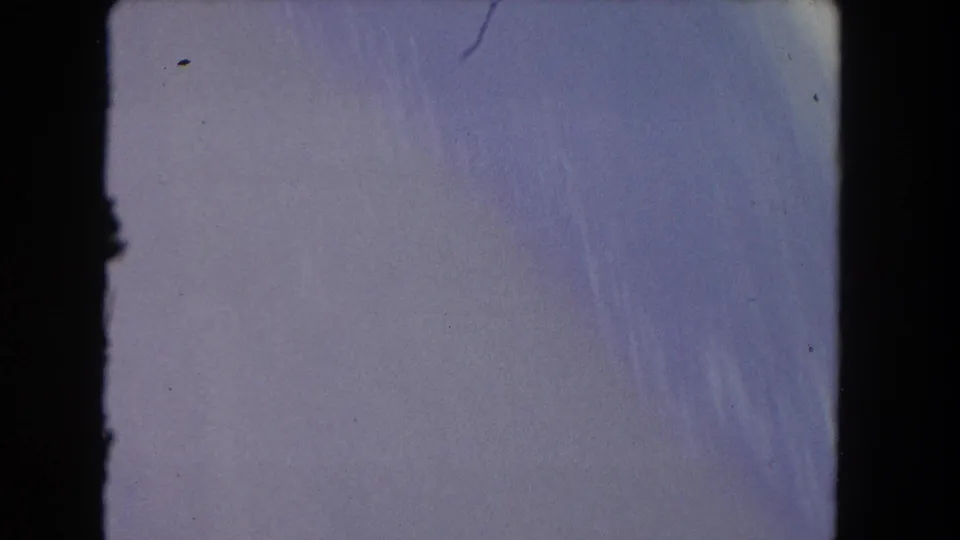End frame from the 8mm scan showing a pale, overexposed film area with faint scratches and dark frame-edge shadows.