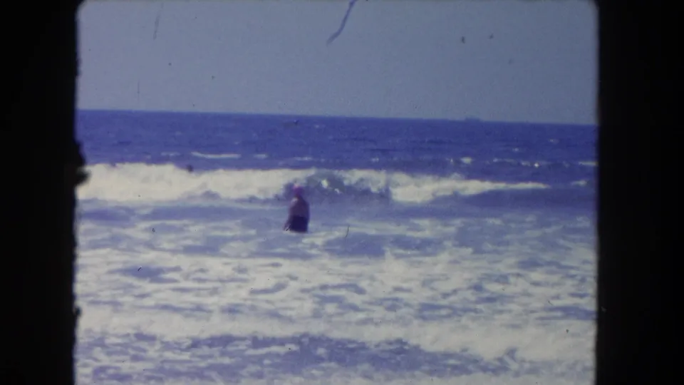 Los Angeles-area 8mm footage from 1962 shows a swimmer bracing in the surf as a wave forms behind them.