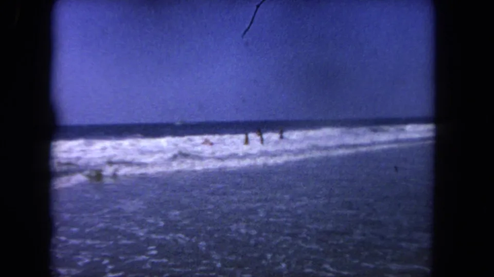 Distant beachgoers wade in the surf during a 1962 Los Angeles coastal home-movie shot.
