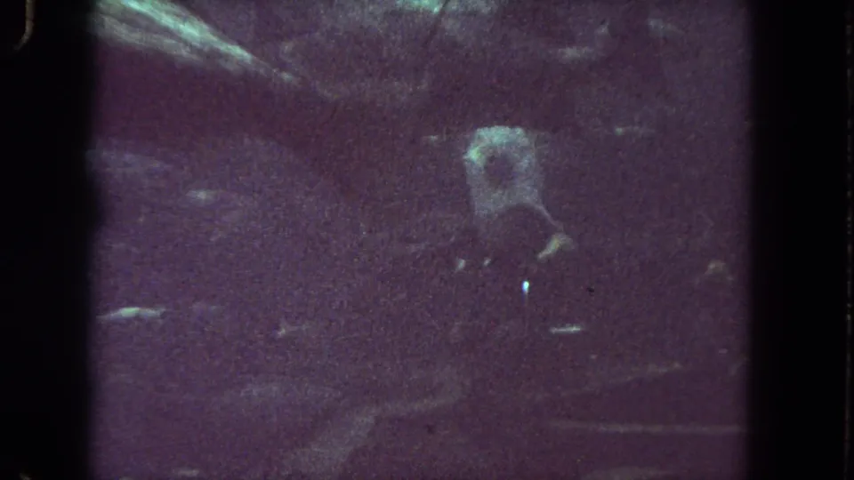 1962 8mm underwater footage from Los Angeles showing dim fish movement and a pale square-lit form in dark water.