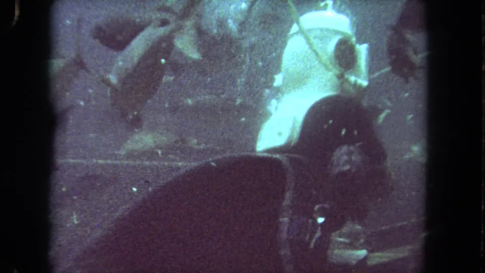1962 Los Angeles underwater home-movie frame with fish around a partly visible diver in dark gear.