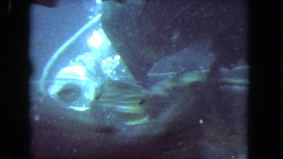 Close 1962 8mm underwater view of scuba equipment, bubbles, and fish in blue-green water.