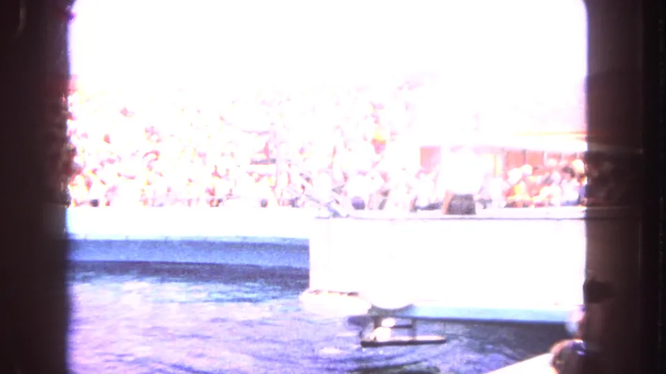 Overexposed 1962 home-movie frame showing water, a crowded marine-show setting, and a washed-out boat area.