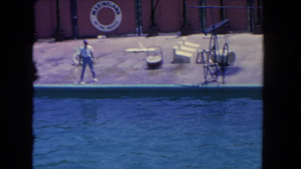 1962 Los Angeles marine-park footage shows a trainer on the pool deck near a Marineland of the Pacific sign and show-pool water.