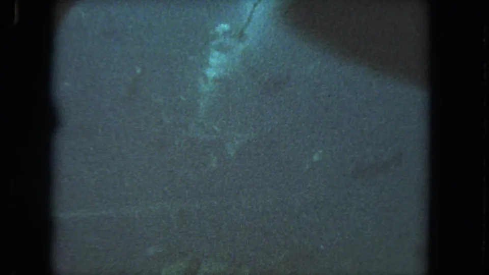 1962 Los Angeles 8mm underwater scene with murky water, a pale indistinct form, and a dark shadow or light leak crossing the frame.