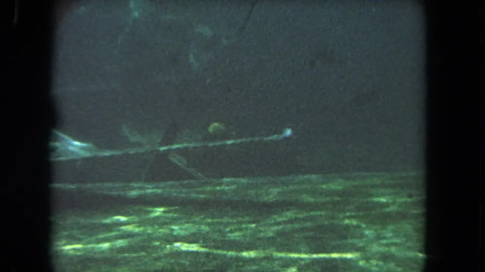 1962 8mm Los Angeles underwater frame showing green reflections, murky water, film borders, and a bright horizontal light streak.