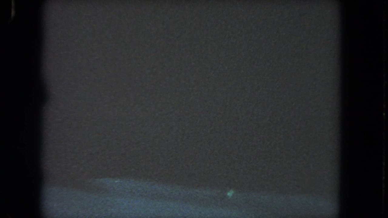 Mostly dark murky underwater frame with blue-green lower water and film borders.