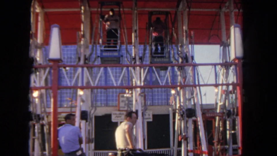 A 1962 Los Angeles amusement-park frame shows raised gondola cars over visitors and the red-and-white ride structure.