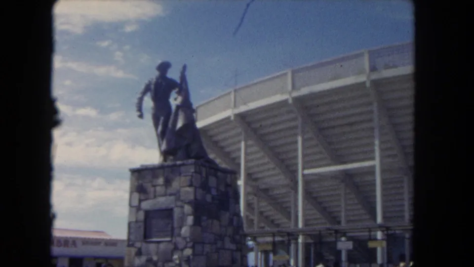 1962 Los Angeles frame showing a cowboy-and-horse monument next to the elevated edge of a public arena or stadium.