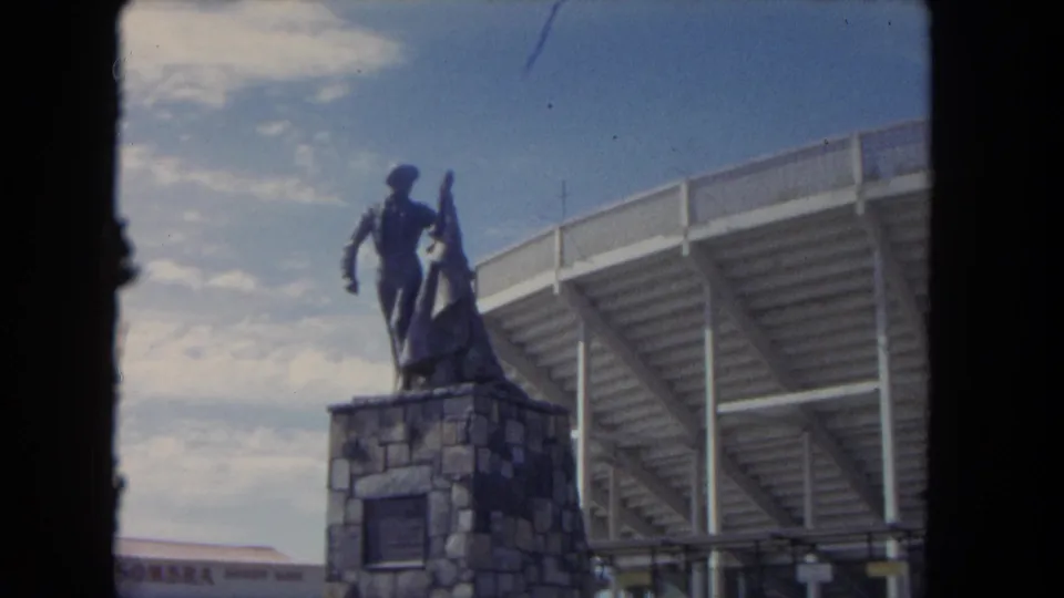 1962 Los Angeles stadium exterior with a matador statue on a stone base and partial signage in the background.
