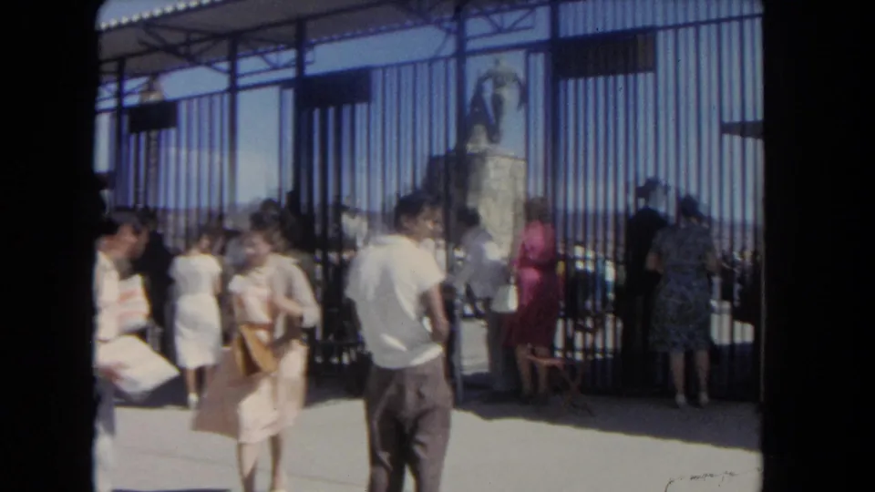 1962 Los Angeles home-movie view of men and women near metal gates at a stadium entrance.