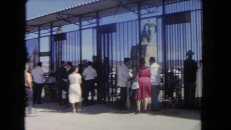 1962 Los Angeles stadium entrance with men and women walking through metal gates beneath a roofed entry area.