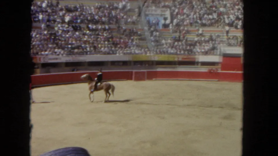 1962 Los Angeles rodeo footage showing a rider on horseback in a sandy arena with spectators behind red barriers.
