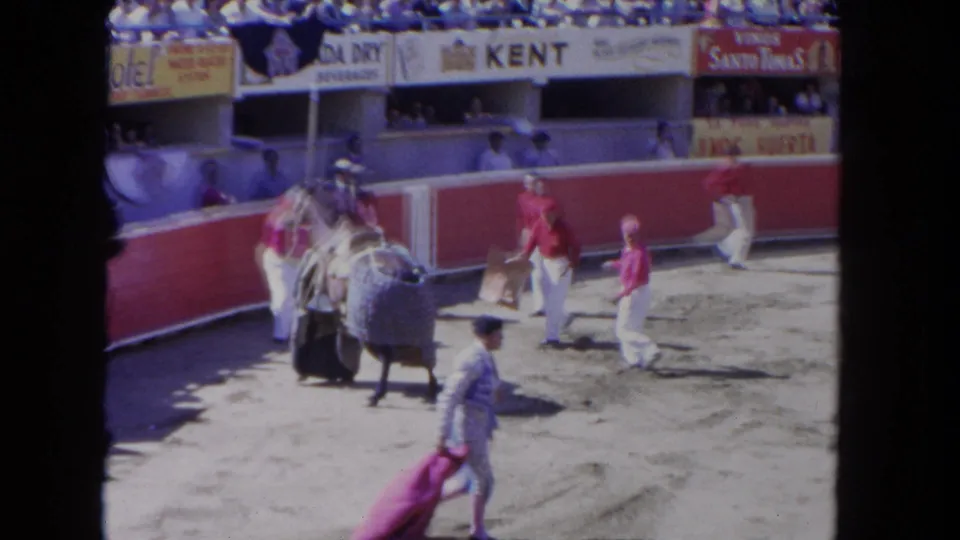 Handlers in a 1962 Los Angeles arena gather around a covered horse as a matador-style figure walks through the foreground.