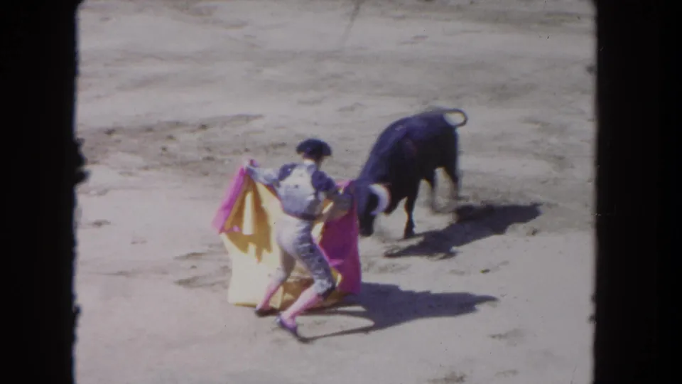 1962 Los Angeles 8mm frame with the black bull close to the matador as the pink and yellow cape is swept low in the arena.