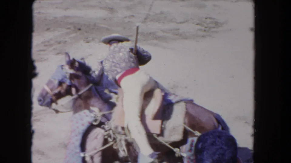 1962 Los Angeles rodeo frame showing a cowboy on horseback turning with a long lance beside another horse in the arena.