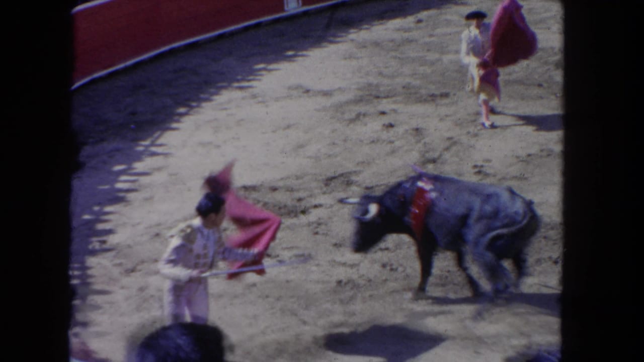 1962 8mm home-movie frame: matador works a magenta cape as a black bull charges in an open-air arena, reportedly in Los Angeles, California.