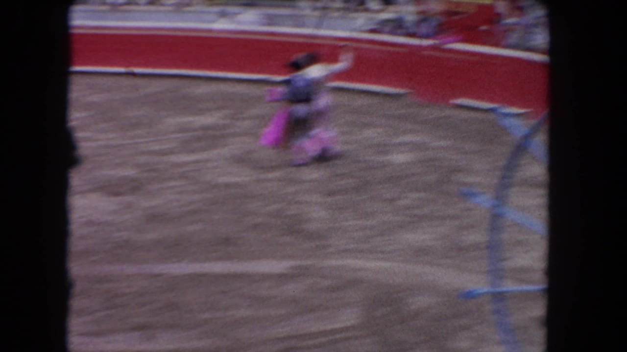1962 bullfighting arena footage: matador in traditional traje de luces in motion with pink capote cape; 8mm film-edge borders visible on sides.