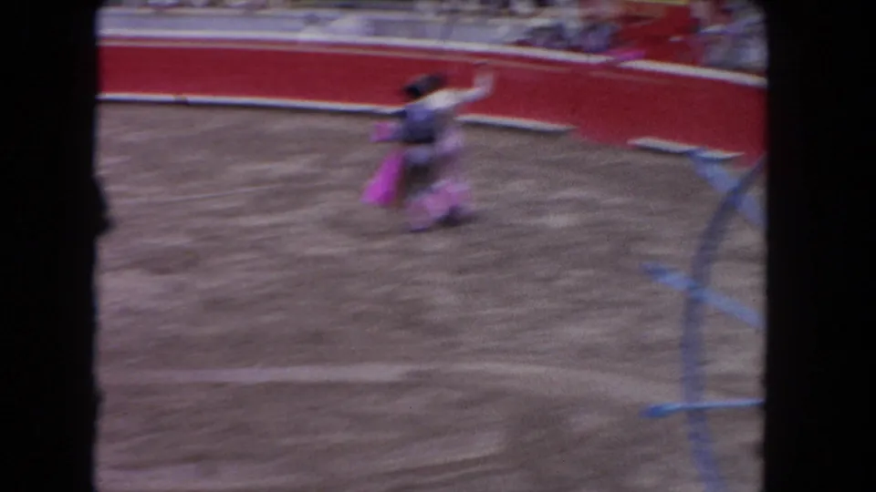 1962 bullfighting arena footage: matador in traditional traje de luces in motion with pink capote cape; 8mm film-edge borders visible on sides.